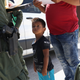 A boy and father from Honduras are taken into custody by U.S. Border Patrol agents near the U.S.-Mexico border near Mission, Texas.